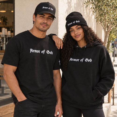 Man wearing an Armor of God trucker cap and Classic T-Shirt beside a woman wearing the cuffed beanie and pullover hoodie